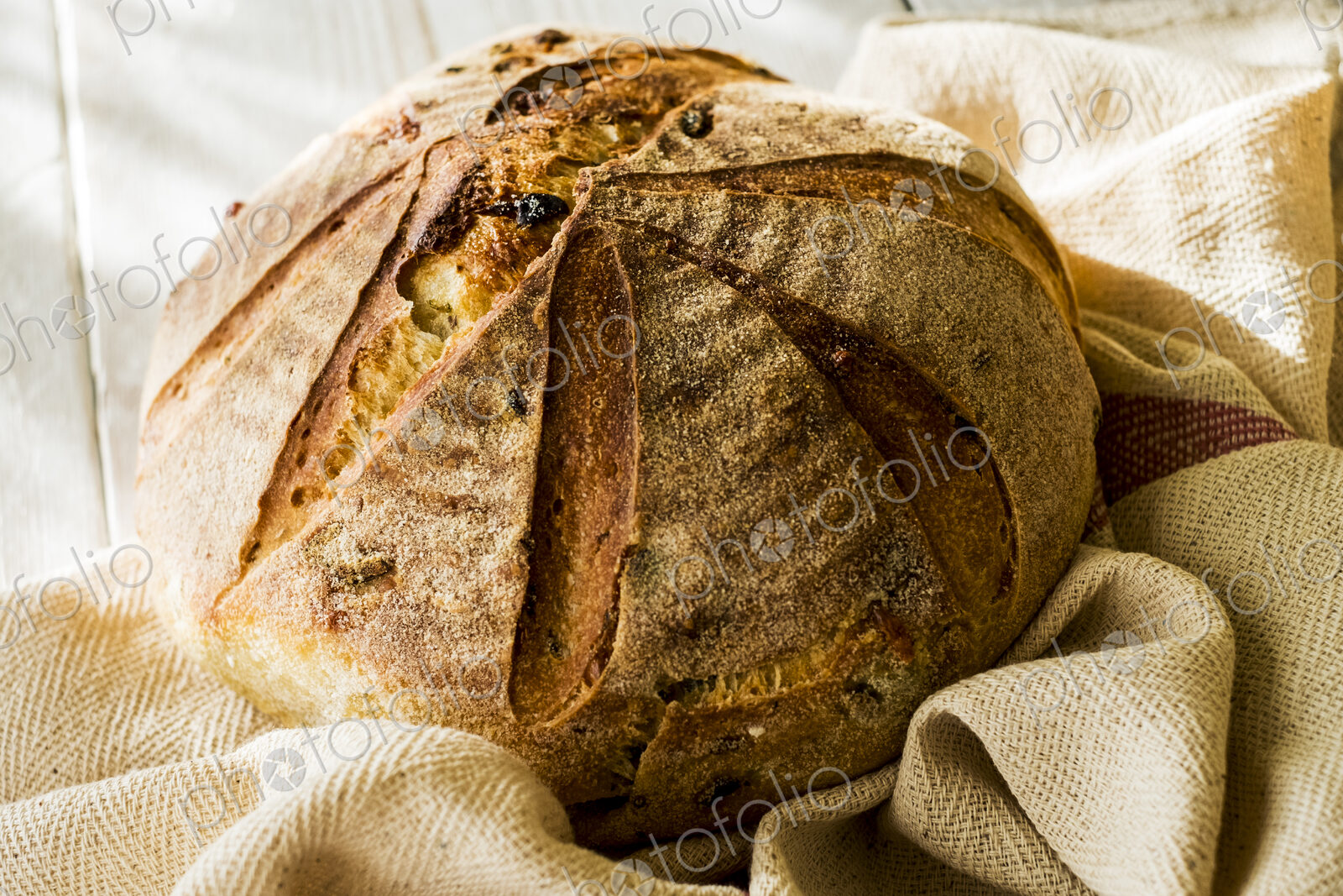High angle close up of a freshly baked round loaf of bread on tea towel.