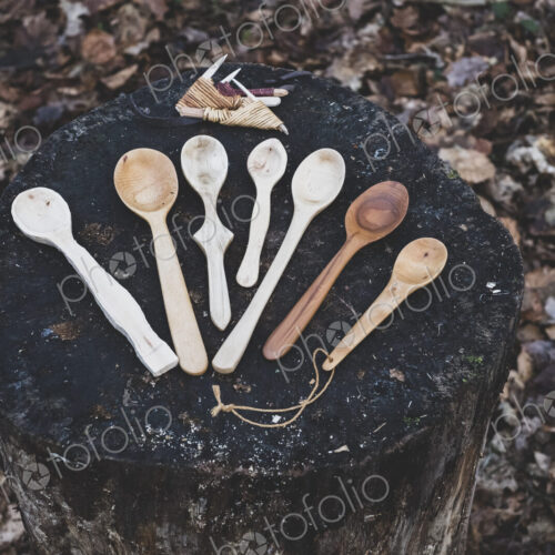 High angle close up of a selection of carved wooden spoons on chopping block.