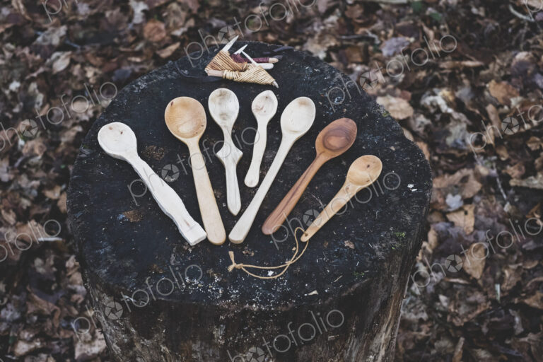 High angle close up of a selection of carved wooden spoons on chopping block.
