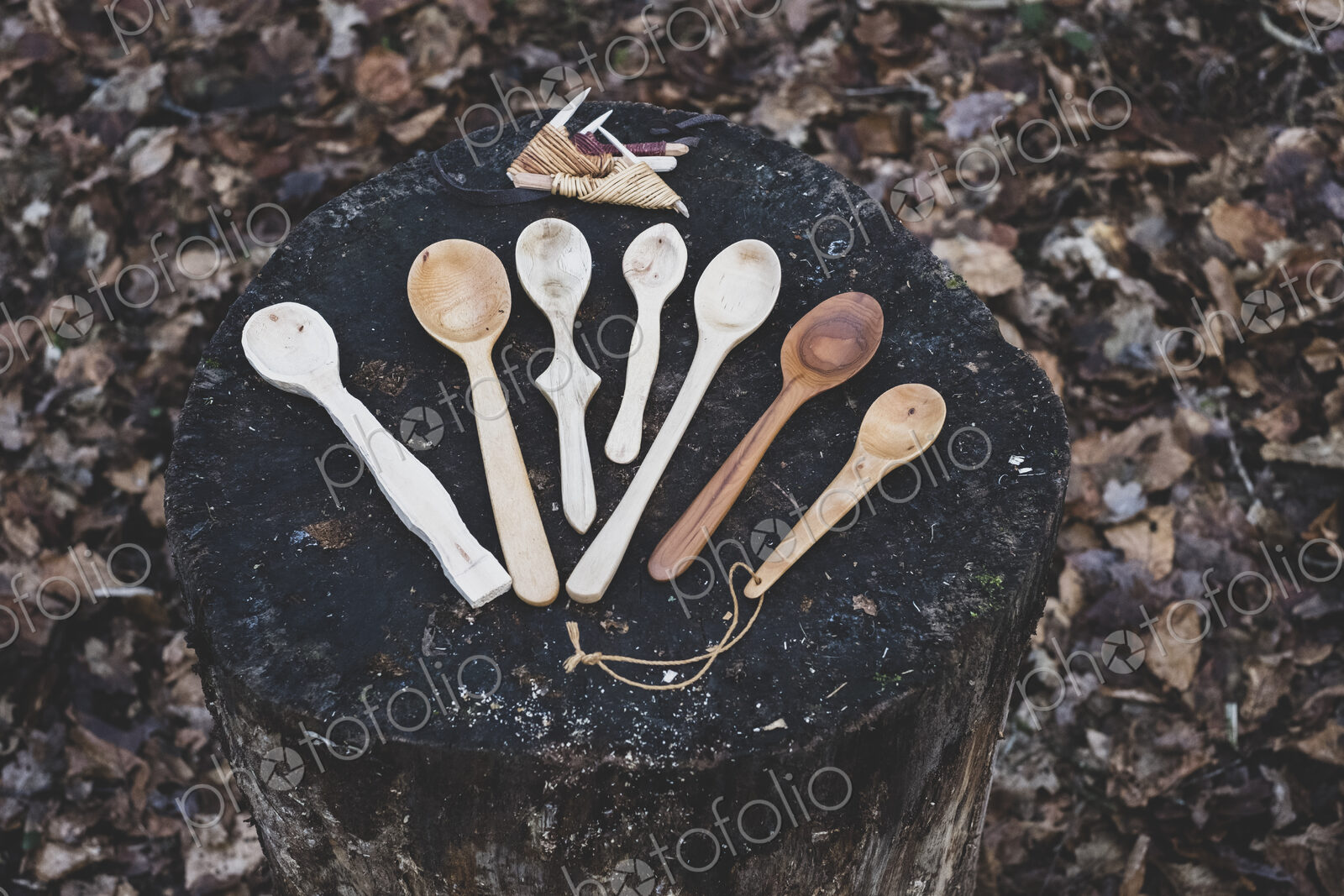 High angle close up of a selection of carved wooden spoons on chopping block.