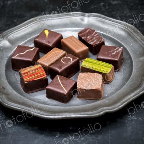 High angle close up of a selection of chocolate pralines on a tin plate on black… High angle close up of a selection of chocolate pralines on a tin plate on black…