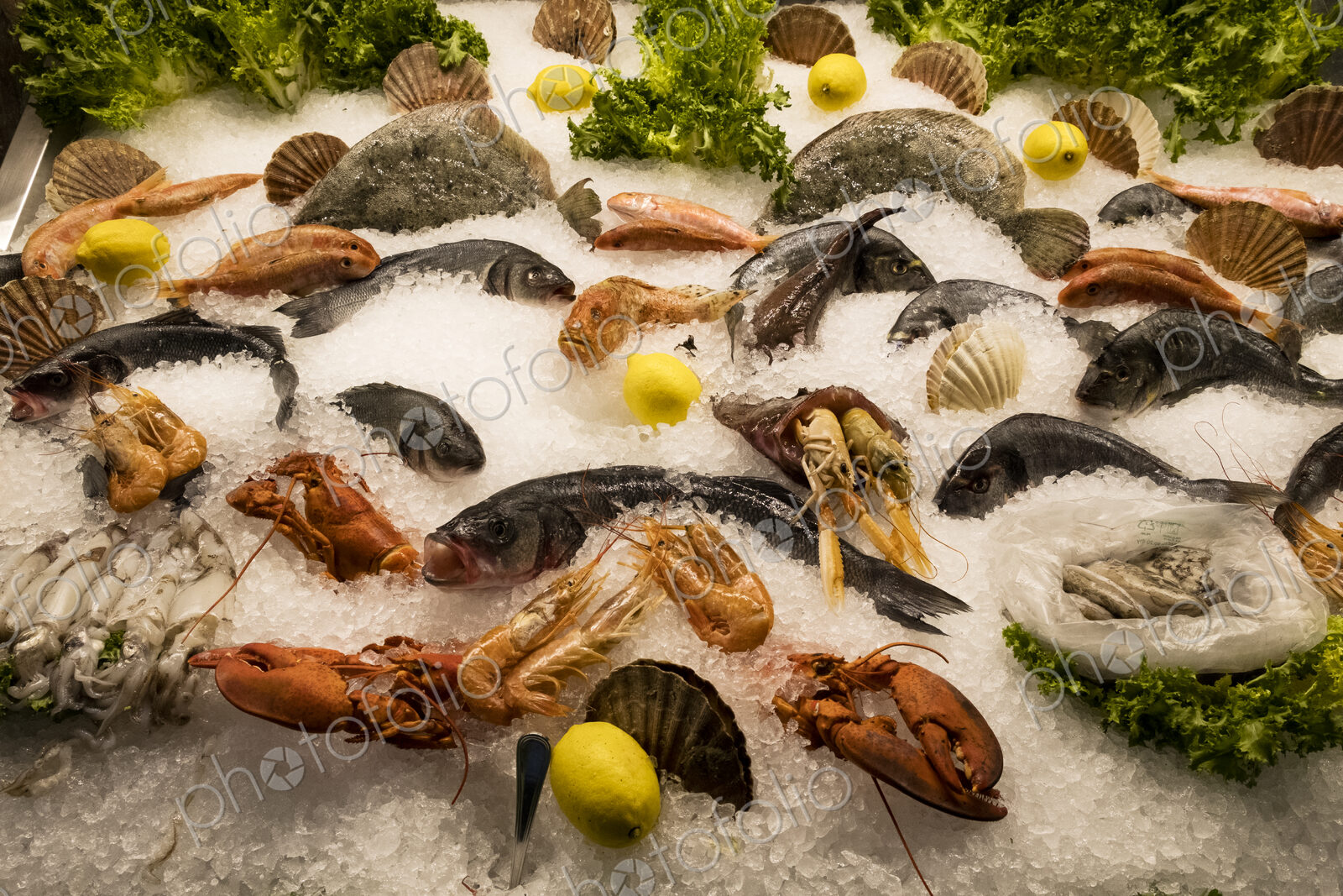 High angle close up of a selection of fresh fish and shellfish on ice at a market stall.