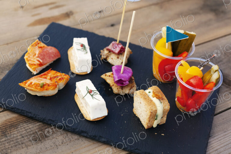 High angle close up of a selection of sandwiches and fresh vegetables on slate tray.