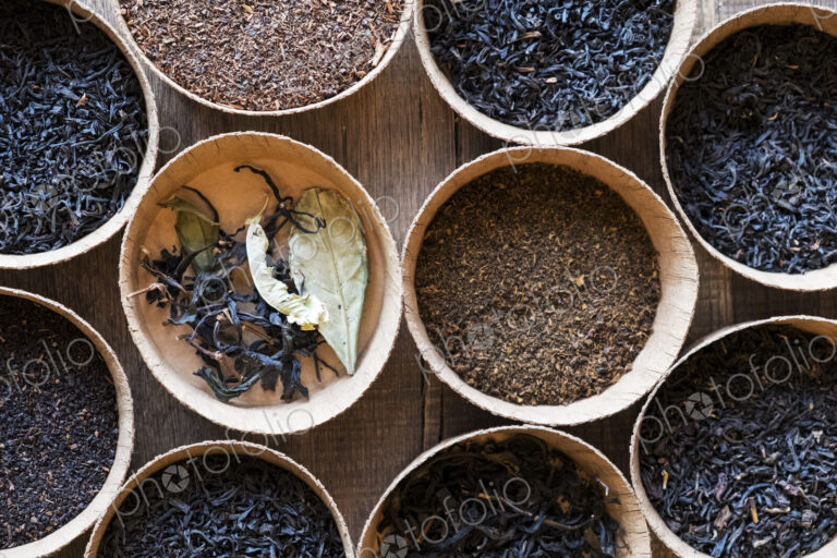 High angle close up of a selection of tea leaves in small wooden bowls.