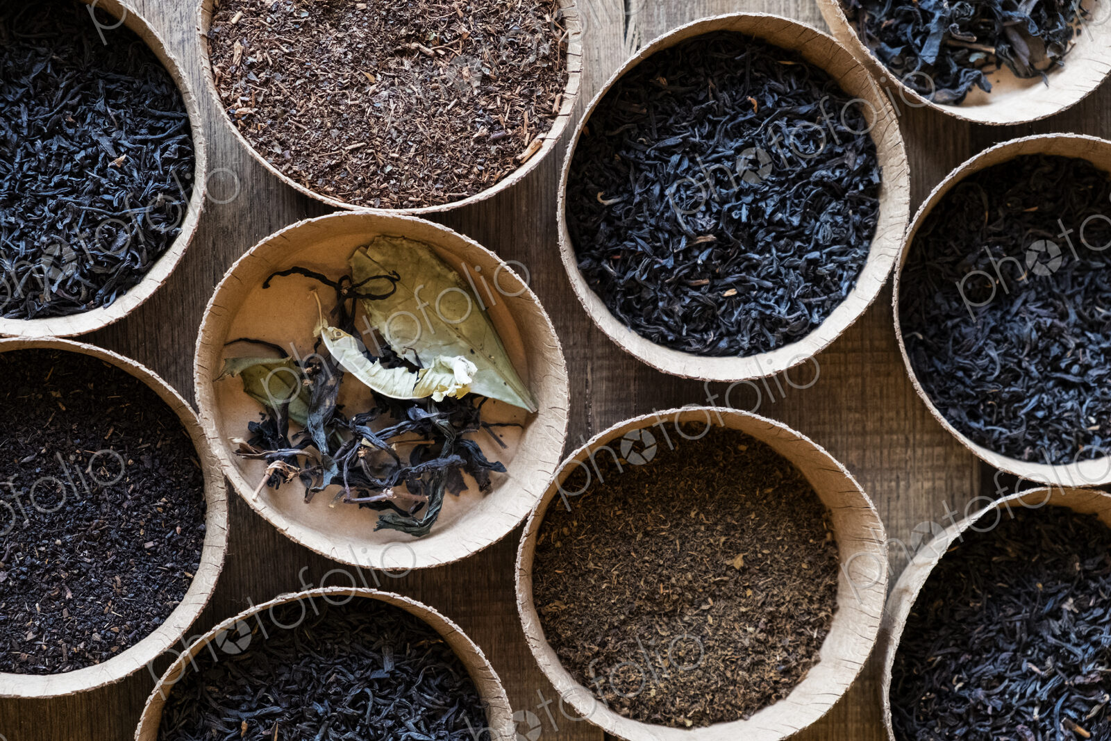 High angle close up of a selection of tea leaves in small wooden bowls.