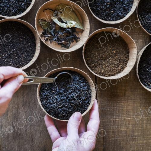 High angle close up of a selection of tea leaves in small wooden bowls.
