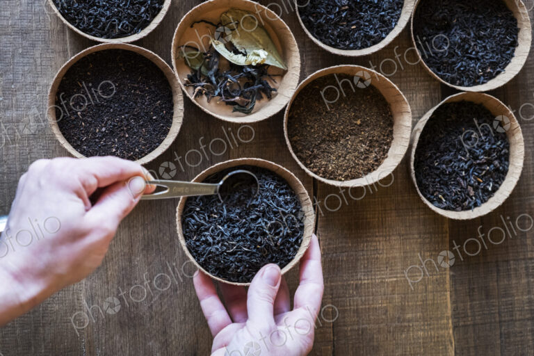 High angle close up of a selection of tea leaves in small wooden bowls.