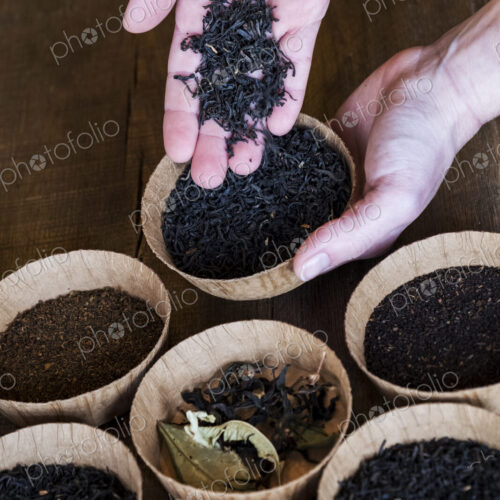 High angle close up of a selection of tea leaves in small wooden bowls.