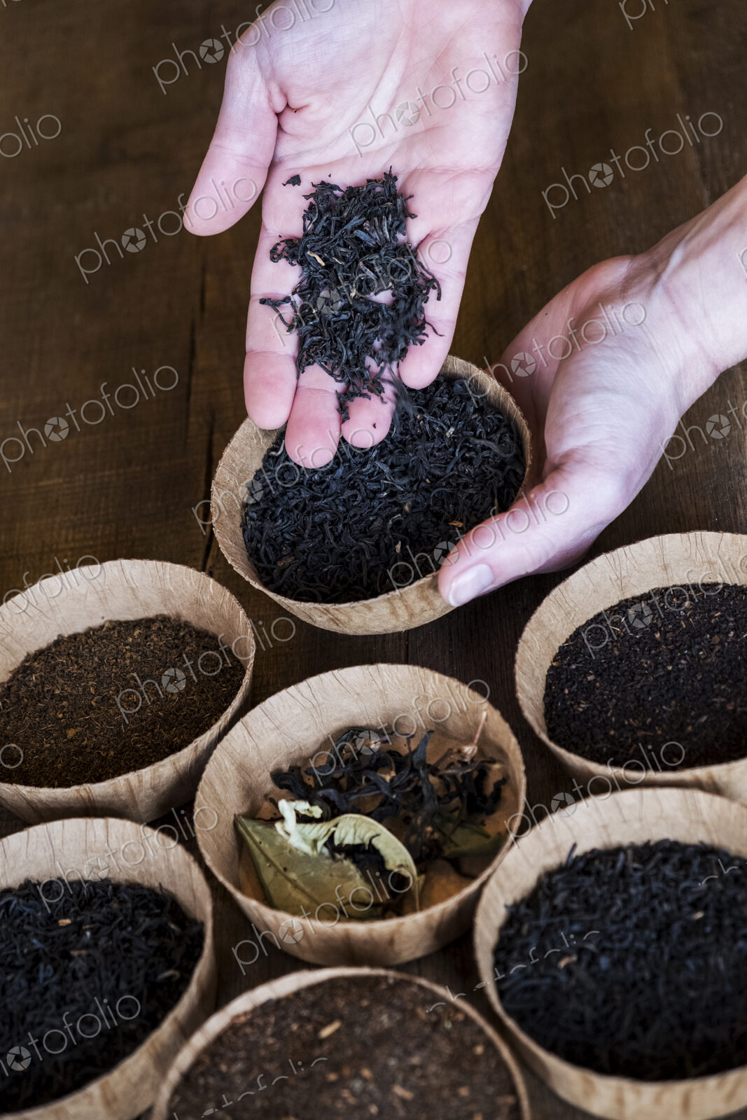 High angle close up of a selection of tea leaves in small wooden bowls.