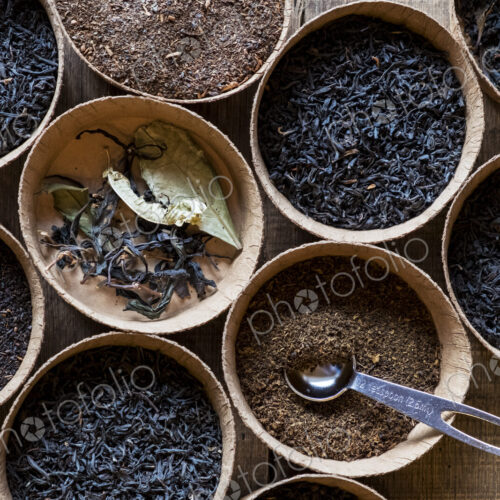 High angle close up of a selection of tea leaves in small wooden bowls.