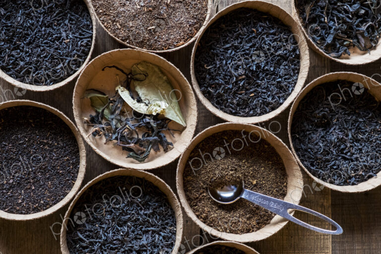 High angle close up of a selection of tea leaves in small wooden bowls.