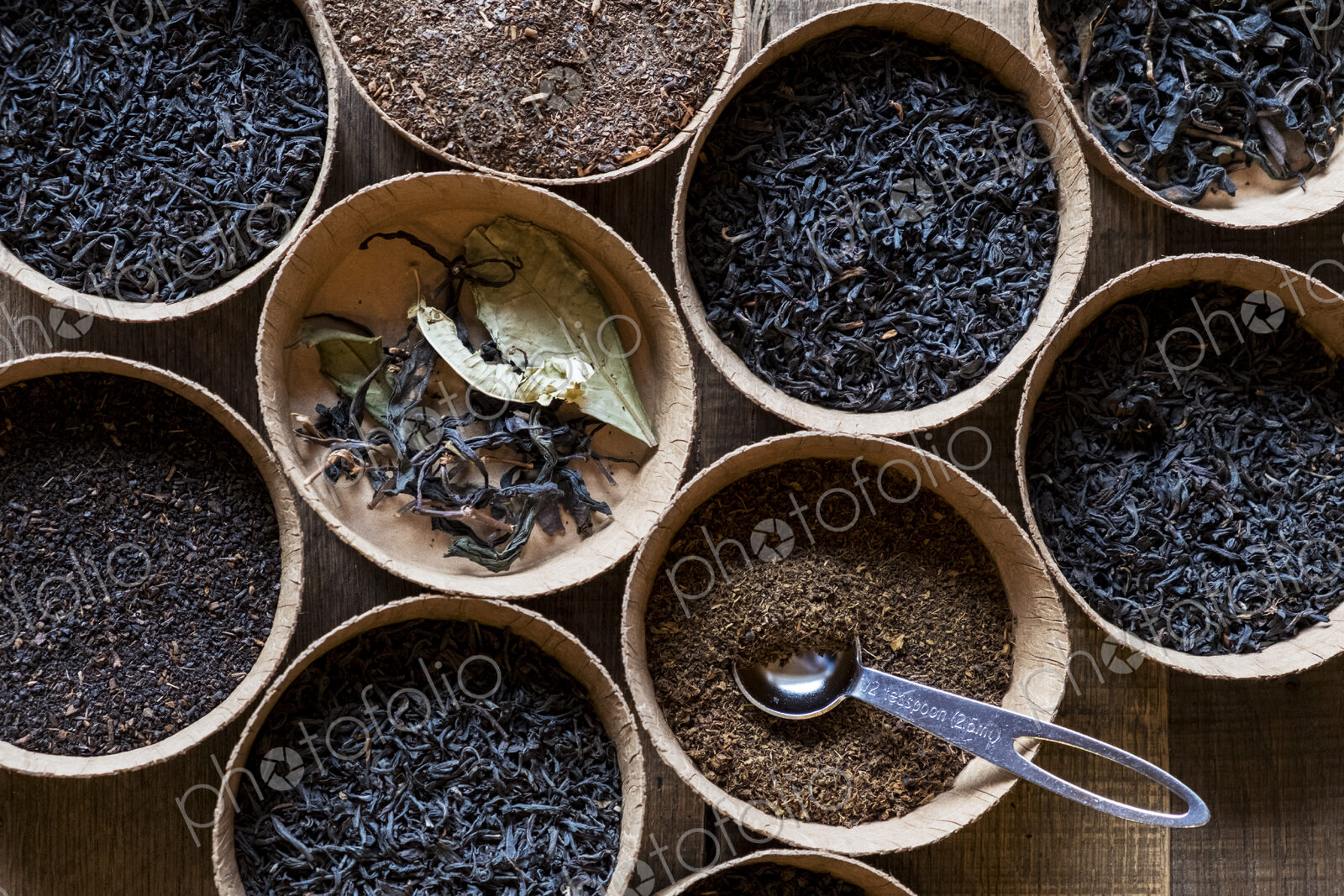 High angle close up of a selection of tea leaves in small wooden bowls.