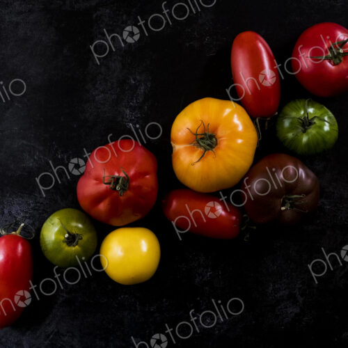 High angle close up of a selection of tomatoes in various shapes and colours on black… High angle close up of a selection of tomatoes in various shapes and colours on black…