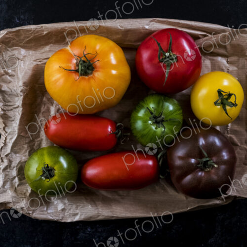 High angle close up of a selection of tomatoes in various shapes and colours on black… High angle close up of a selection of tomatoes in various shapes and colours on black…