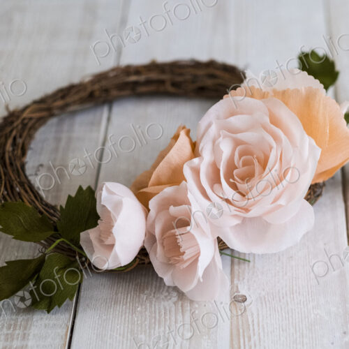 High angle close up of a small wreath with pale and salmon pink paper roses. High angle close up of a small wreath with pale and salmon pink paper roses.