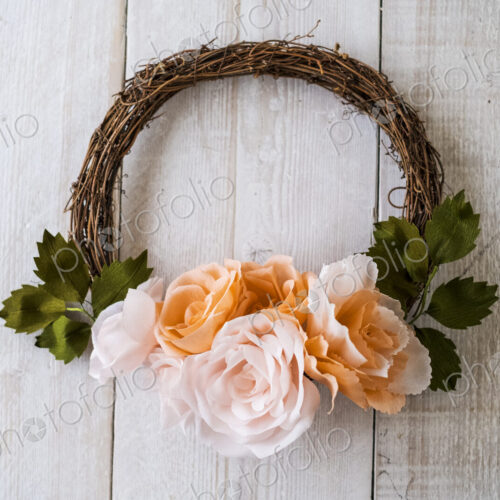 High angle close up of a small wreath with pale and salmon pink paper roses. High angle close up of a small wreath with pale and salmon pink paper roses.