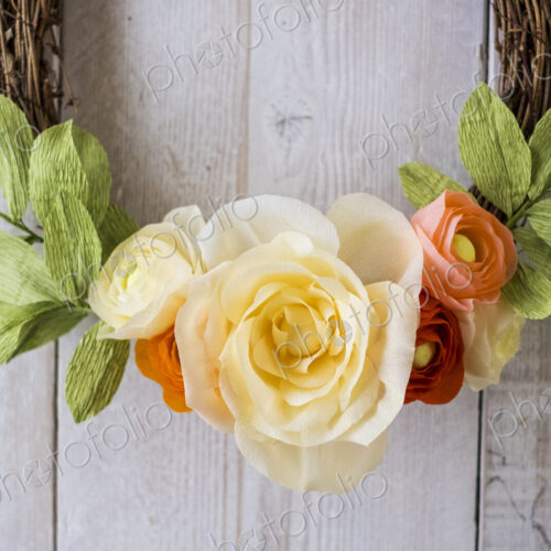 High angle close up of a small wreath with pale yellow and pink paper roses. High angle close up of a small wreath with pale yellow and pink paper roses.