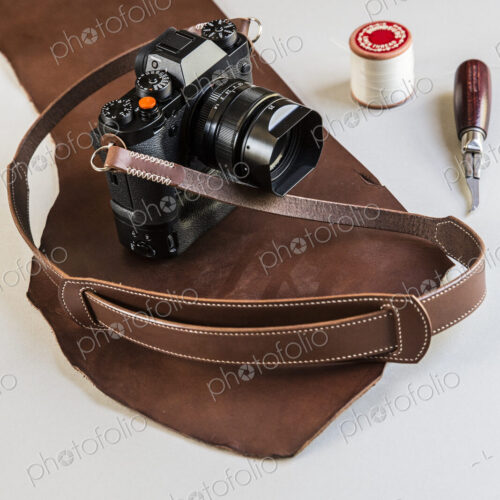 High angle close up of a vintage camera with handmade brown leather strap. High angle close up of a vintage camera with handmade brown leather strap.