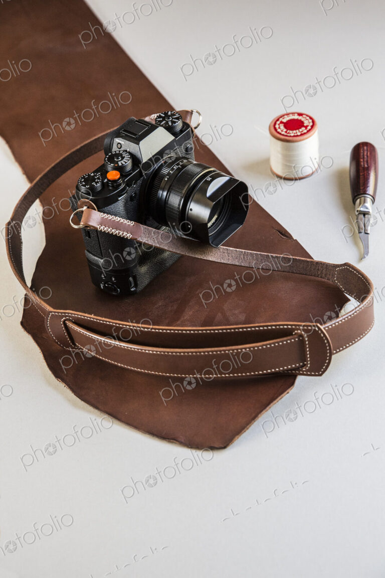 High angle close up of a vintage camera with handmade brown leather strap.