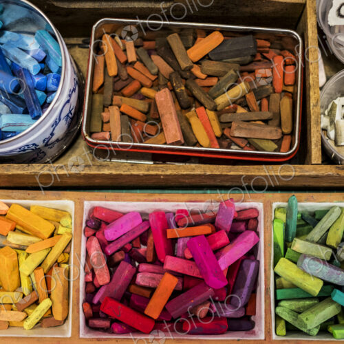 High angle close up of a wooden box with artist's crayons in a variety of vibrant colours.