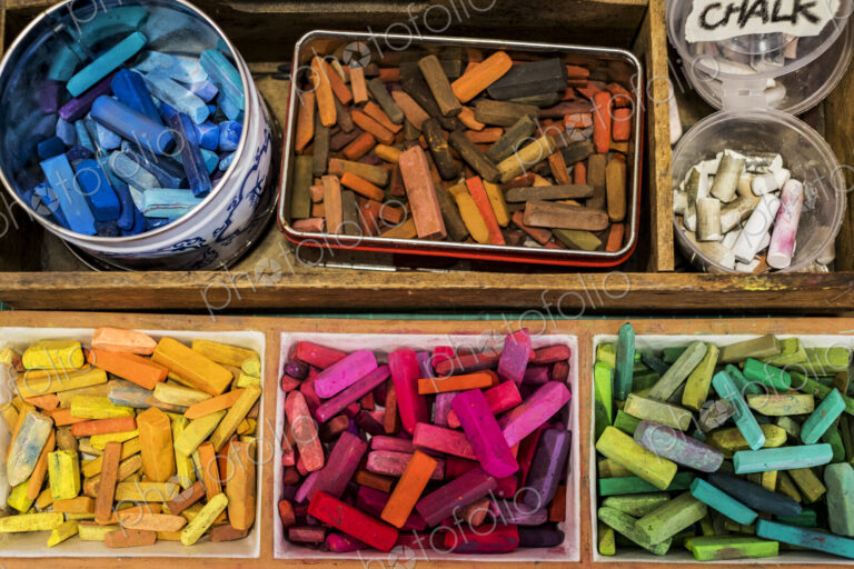 High angle close up of a wooden box with artist's crayons in a variety of vibrant colours.