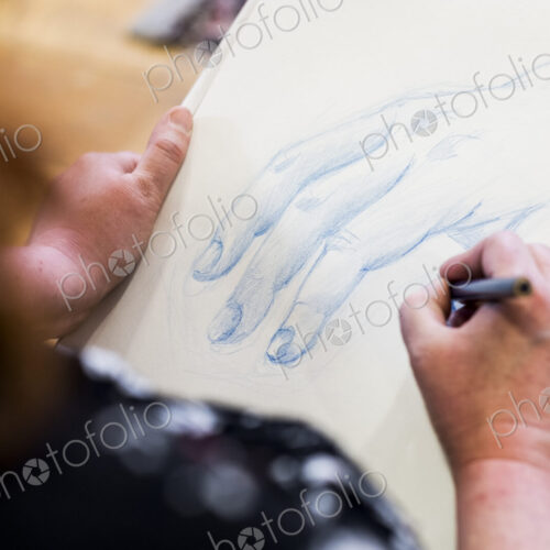 High angle close up of artist drawing human hand.