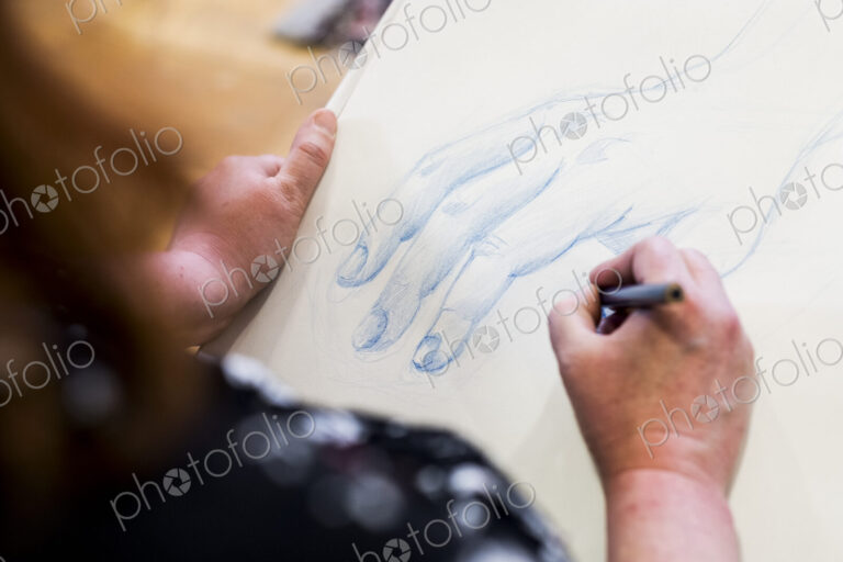 High angle close up of artist drawing human hand.