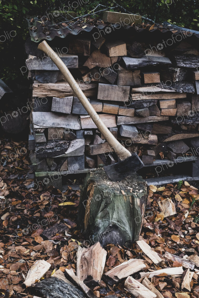 High angle close up of axe on chopping block, scattered wood cuttings and autumn leaves.