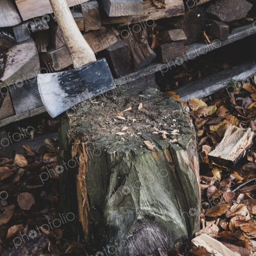 High angle close up of axe on chopping block, scattered wood cuttings and autumn leaves. High angle close up of axe on chopping block, scattered wood cuttings and autumn leaves.