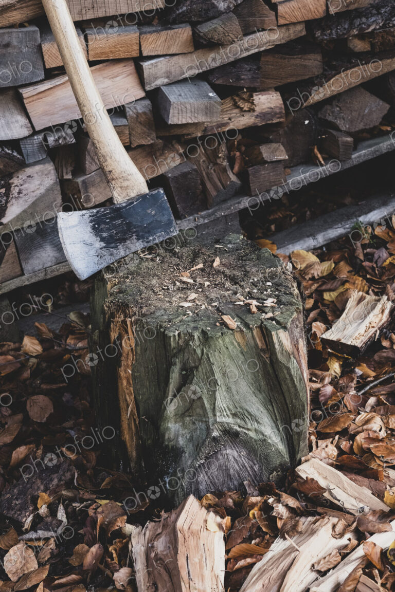 High angle close up of axe on chopping block, scattered wood cuttings and autumn leaves.