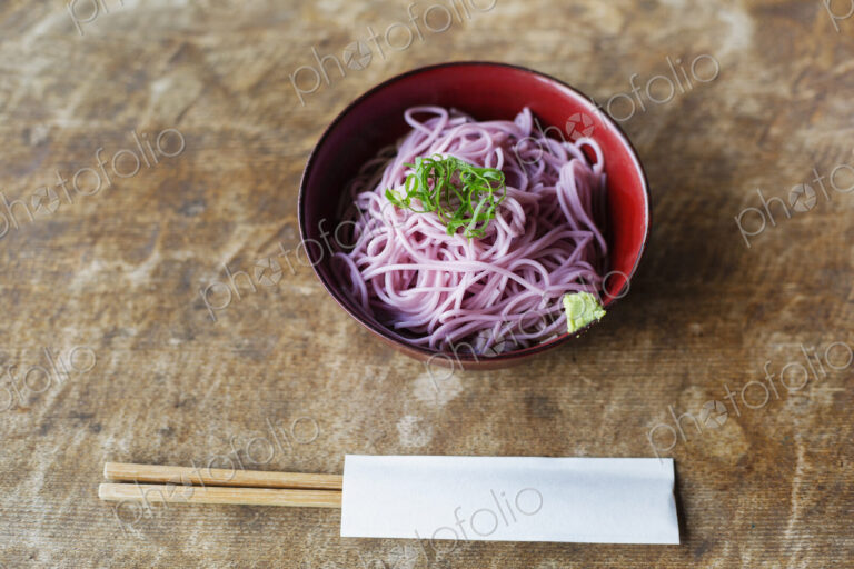 High angle close up of bowl of pink noodles on a table in Japanese restaurant.