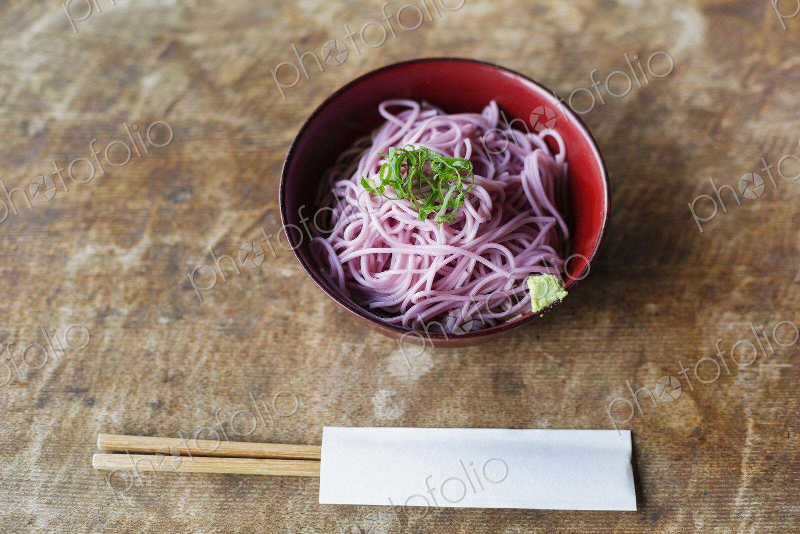 High angle close up of bowl of pink noodles on a table in Japanese restaurant.