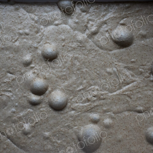 High angle close up of bread dough with air bubbles in an artisan bakery.