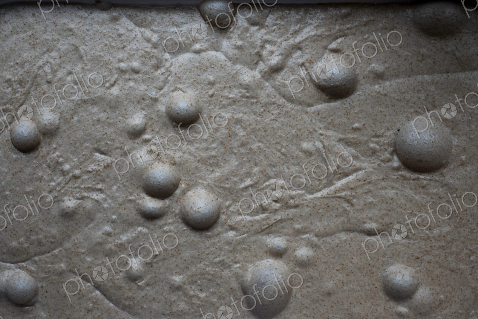 High angle close up of bread dough with air bubbles in an artisan bakery.