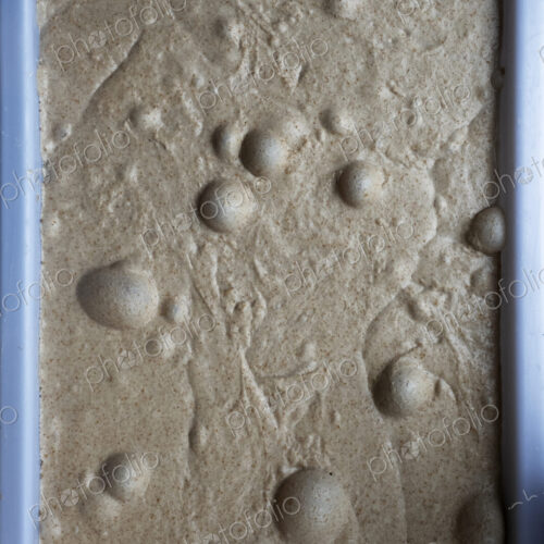 High angle close up of bread dough with air bubbles in an artisan bakery.