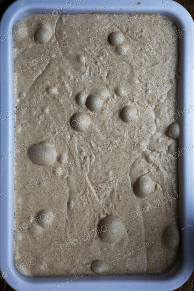 High angle close up of bread dough with air bubbles in an artisan bakery.