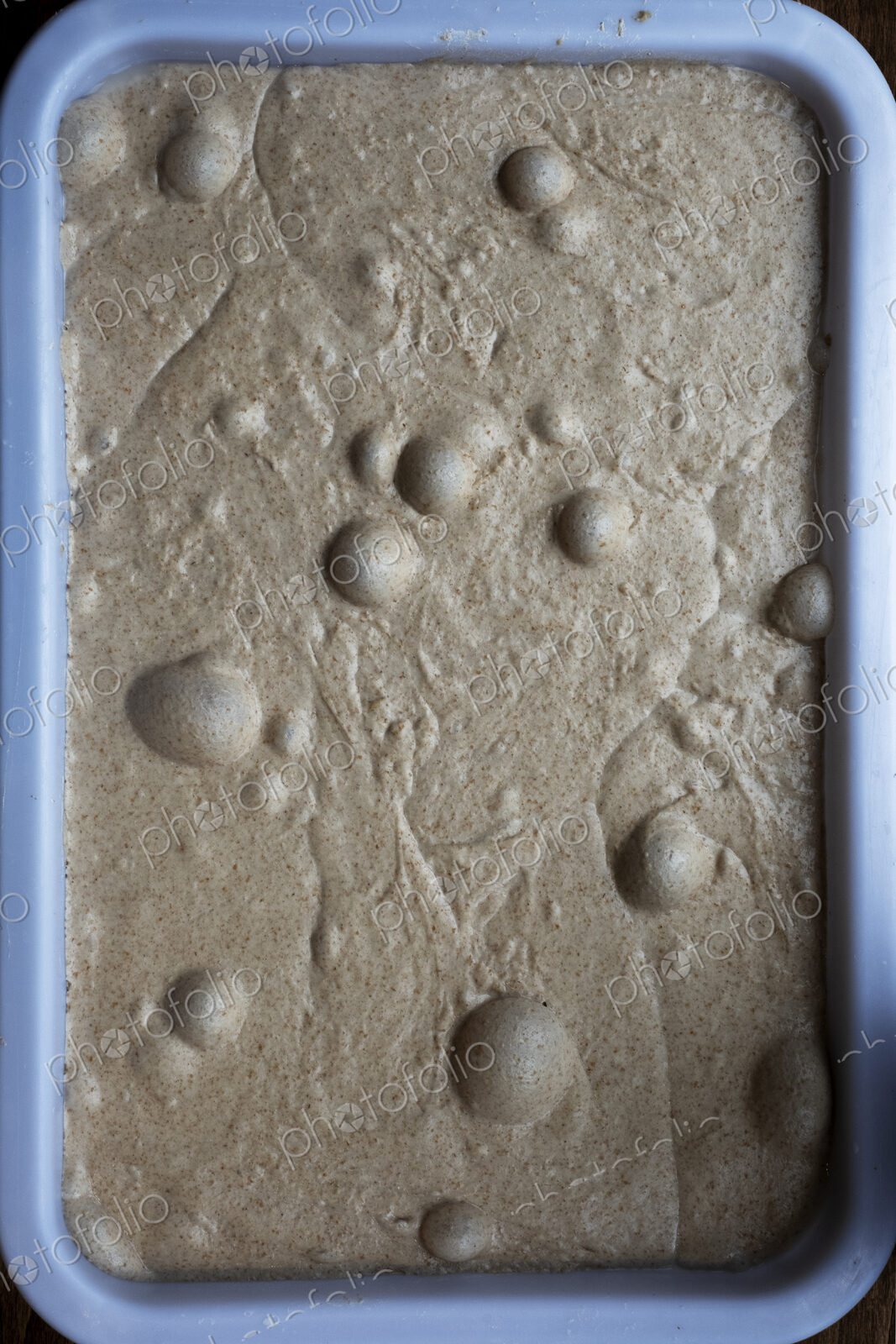 High angle close up of bread dough with air bubbles in an artisan bakery.