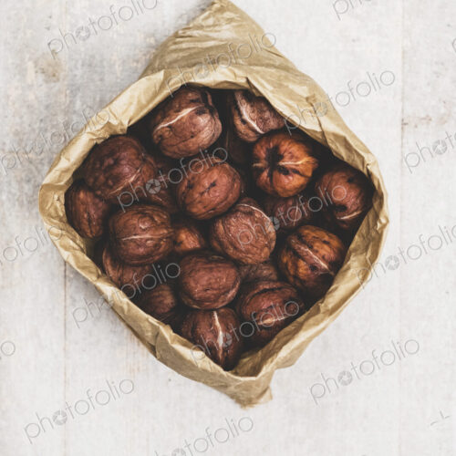 High angle close up of brown paper bag with fresh walnuts. High angle close up of brown paper bag with fresh walnuts.