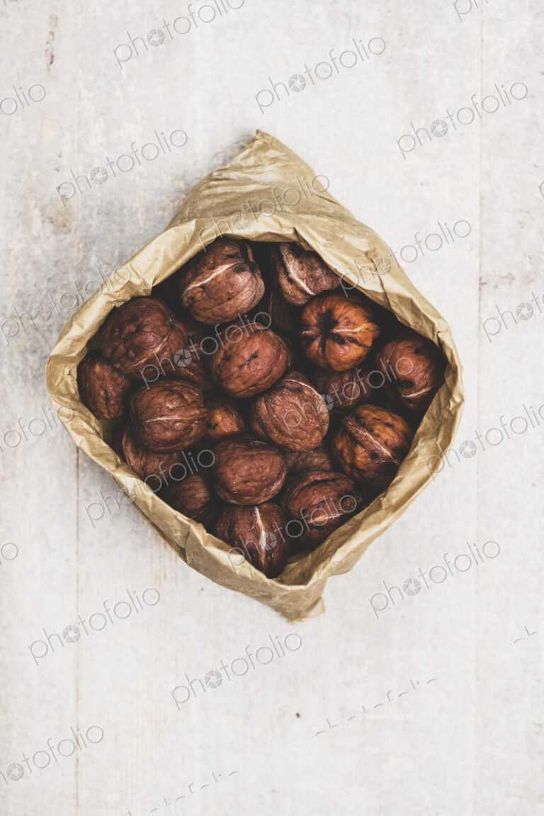 High angle close up of brown paper bag with fresh walnuts.