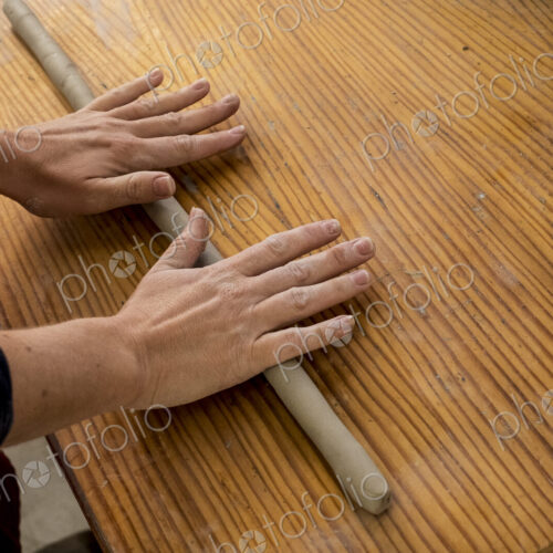 High angle close up of ceramic artist in her workshop, rolling out piece of clay on…