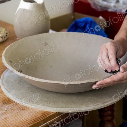 High angle close up of ceramic artist in her workshop, working on clay bowl.