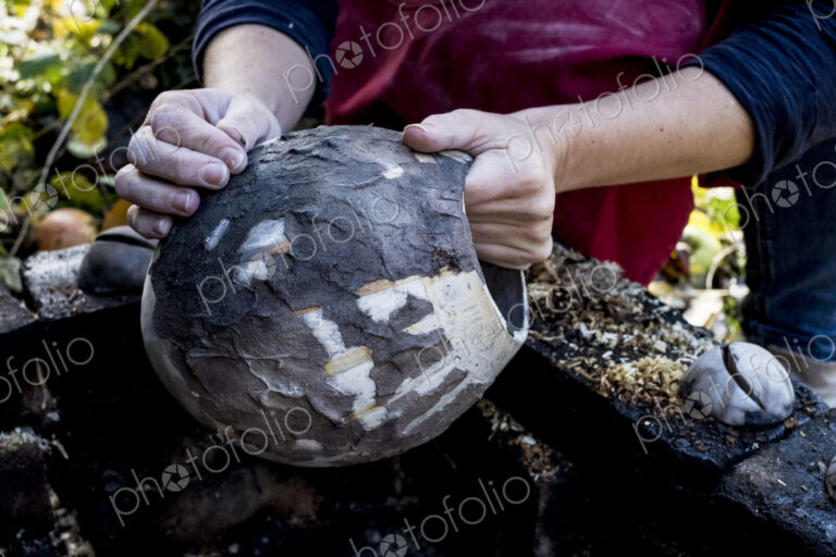 High angle close up of ceramic artist sitting outdoors, working on vase.