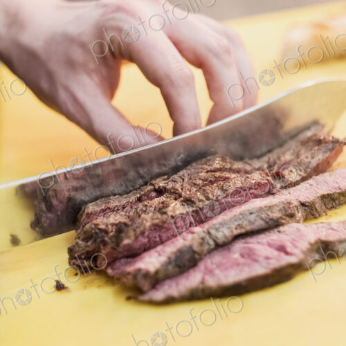 High angle close up of chef slicing beef with kitchen knife. High angle close up of chef slicing beef with kitchen knife.