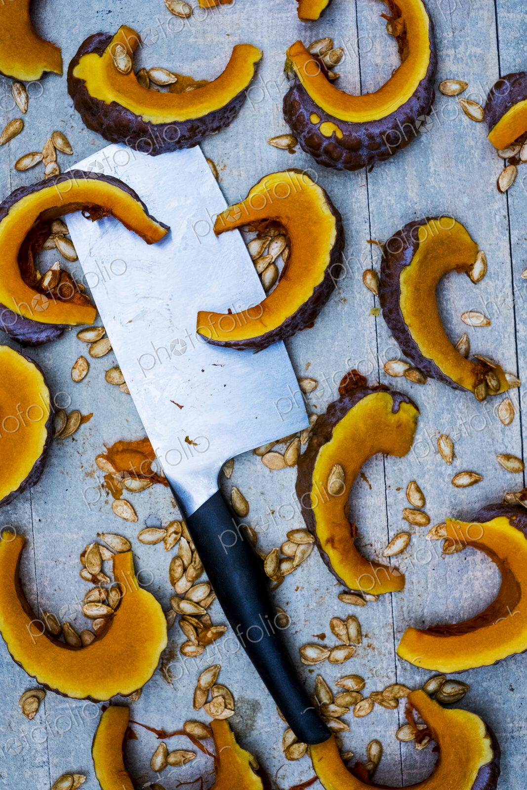 High angle close up of cleaver and slices of pumpkin on blue background.