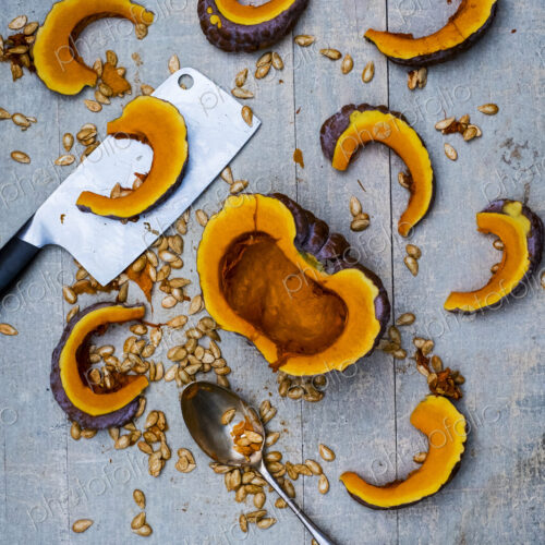 High angle close up of cleaver, silver tablespoon and slices of pumpkin on blue…