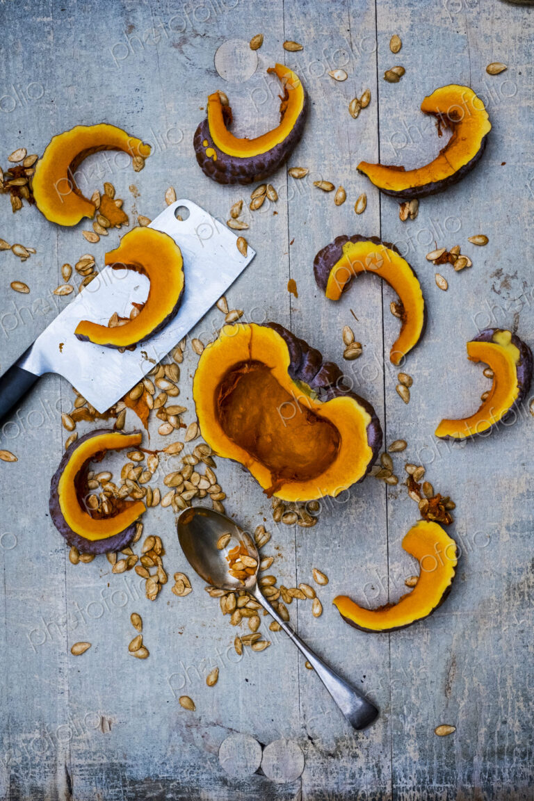 High angle close up of cleaver, silver tablespoon and slices of pumpkin on blue…