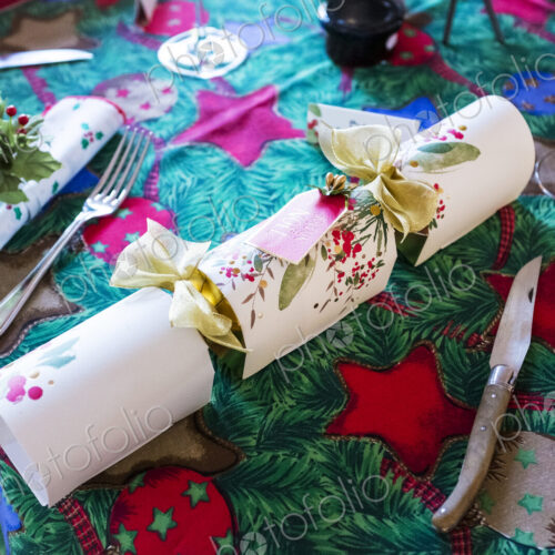 High angle close up of cutlery and white Christmas cracker, Christmas table setting High angle close up of cutlery and white Christmas cracker, Christmas table setting
