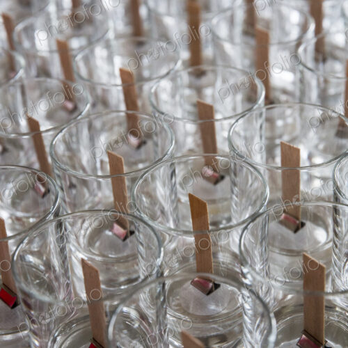 High angle close up of empty glass jars with wooden wicks, for candle making. High angle close up of empty glass jars with wooden wicks, for candle making.