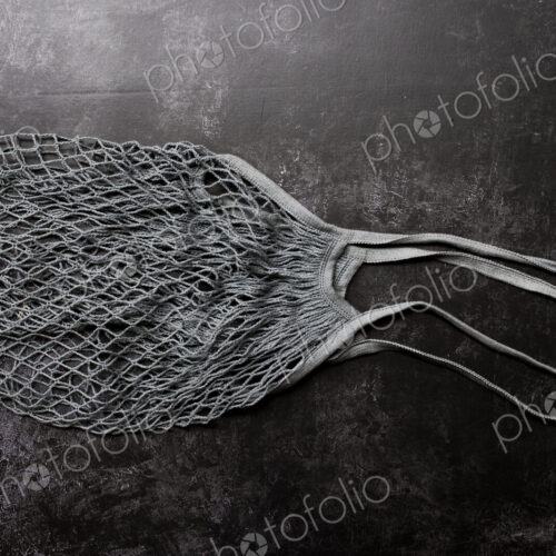 High angle close up of empty grey net bag on black background. High angle close up of empty grey net bag on black background.