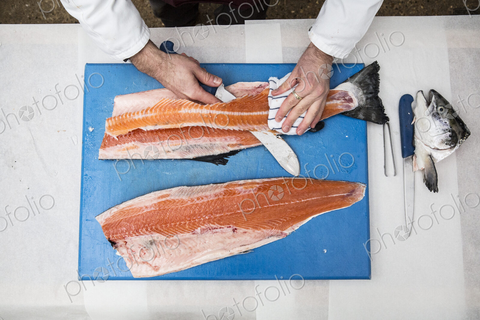 High angle close up of fishmonger standing at a table, cutting and filleting fresh…